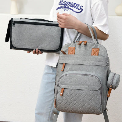 sac à dos à langer gris porté à la main